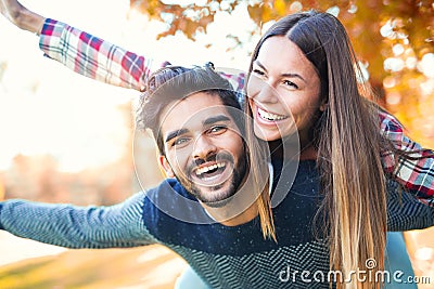 Couple having fun man giving piggyback to woman in park Stock Photo