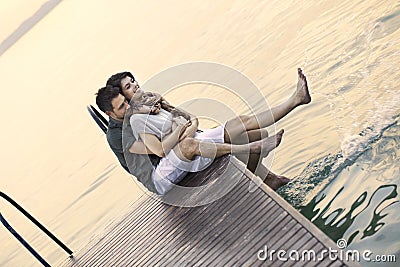 Couple having fun seated on a boardwak with a beautifull lake view Stock Photo