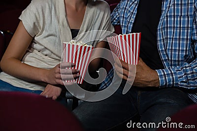 Couple having popcorn while watching movie in theatre Stock Photo