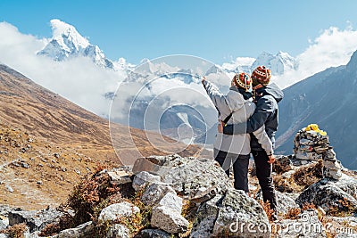 Couple having a rest on Everest Base Camp trekking route near Dughla 4620m. Backpackers left Backpacks, embracing and enjoying Stock Photo