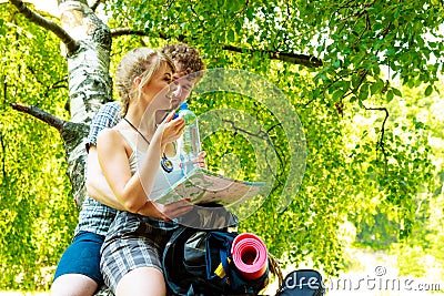 Couple hikers resting in forest drinking water Stock Photo