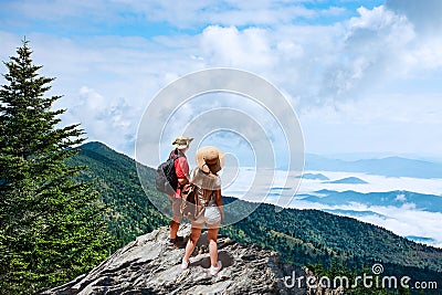 Couple on hiking trip, standing on top of the mountain over the clouds Stock Photo