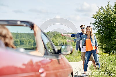 Couple hitchhiking and stopping car on countryside Stock Photo