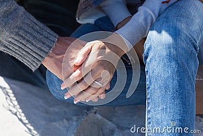Couple holding hands sitting on sand Stock Photo
