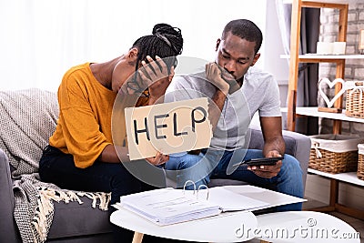 Couple Holding Help Sign While Calculating Bills Stock Photo