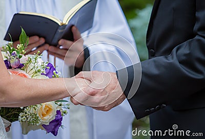 Couple holds hands while saying vows during wedding Stock Photo