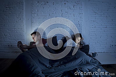 Couple at home in bed late at night using mobile phone in relationship communication problem Stock Photo