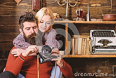 Couple hugs in wooden vintage interior. Man with beard, photographer on busy face holds old fashioned camera. Couple in Stock Photo