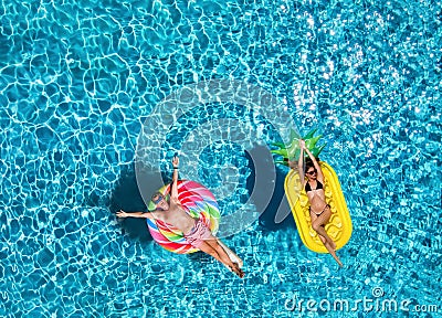 Couple on inflatable floats over blue pool water Stock Photo