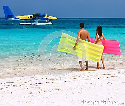 Couple with inflatable rafts looking at seaplane on beach Stock Photo