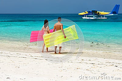 Couple with inflatable rafts looking at seaplane on beach Stock Photo