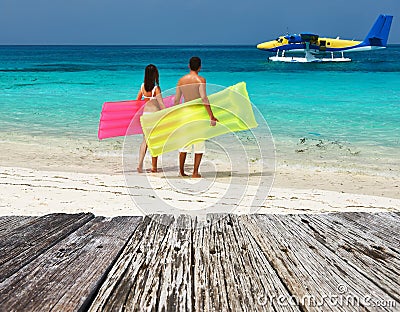 Couple with inflatable rafts looking at seaplane on beach Stock Photo