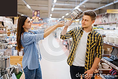 Couple jokes with ladle and pan in houseware store Stock Photo