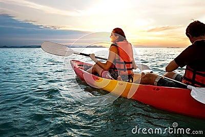 Couple kayaking together. Beautiful young couple kayaking on lake together and smiling at sunset Stock Photo