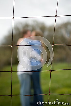 Couple kissing behind a fence Stock Photo