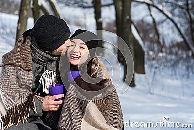 Couple kissing under plaid in winter park Stock Photo