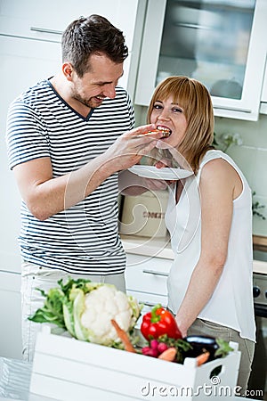 Couple in kitchen, eating bread with tomato Stock Photo