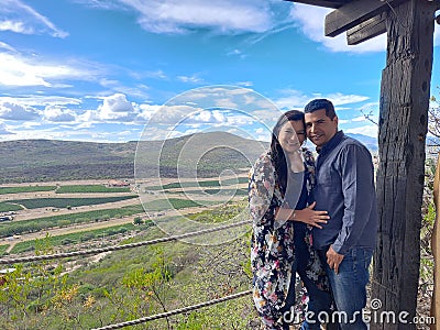 Couple of Latin adult man and woman enjoy the mountainous view of vineyards from a viewpoint you can see the land planted with vin Stock Photo