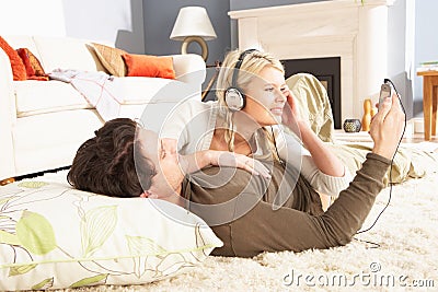 Couple Listening To MP3 Player Laying On Rug Stock Photo
