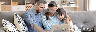 Couple and little daughter using computer watching cartoons on-line Stock Photo