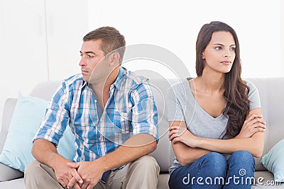 Couple looking away while sitting on sofa Stock Photo