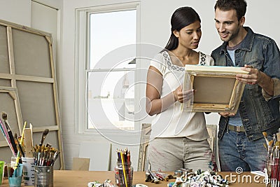 Couple Looking At Canvases In Artist Studio Stock Photo
