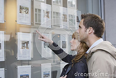 Couple Looking At Display At Real Estate Office Stock Photo