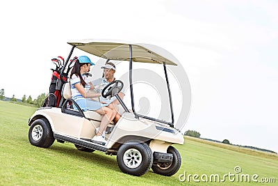 Couple looking at each other while sitting in golf cart against clear sky Editorial Stock Photo