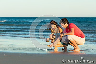 Couple looking for shells at sunset Stock Photo