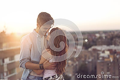 Couple in love on a building rooftop at sunset Stock Photo