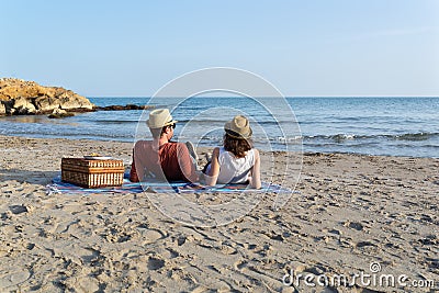 Couple in love having a picnic on a mediterranean beach at sunset Stock Photo