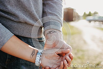 The couple in love holding hand in hand. Paired tattoo initials on the arms Stock Photo