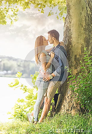 Couple in love on the lake, beneath the trees, kissing Stock Photo