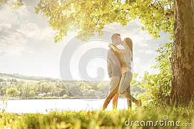 Couple in love on the lake, beneath the trees, kissing Stock Photo