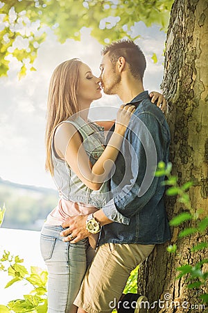 Couple in love on the lake, beneath the trees, kissing Stock Photo