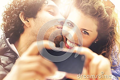 Couple in love making a selfie while him giving her a kiss Stock Photo