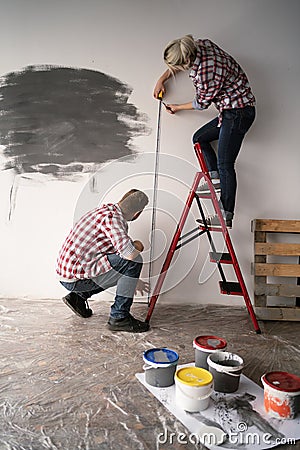 Couple in love measuring the walls in a room. Tape measure and pencil in women's hands. Couple measuring wall in new Stock Photo