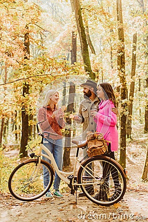Couple in love ride bicycle together in forest park. Friends with bicycle. Bearded man and women relaxing in autumn Stock Photo