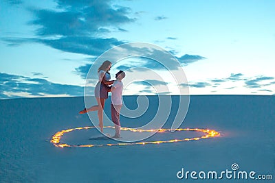 Couple in love romantic hugs in sand desert. Evening, romantic atmosphere, in sand burn candles in form of heart Stock Photo