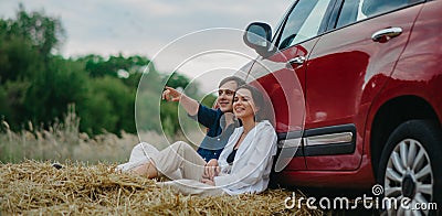 Couple in love sits and has fun on haystack near car Stock Photo