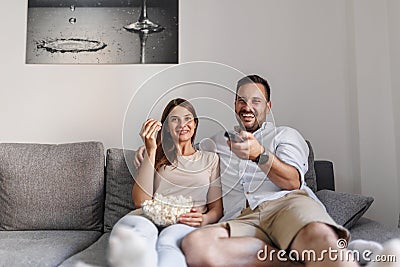 Couple having fun watching TV at home, binging TV shows on weekend Stock Photo