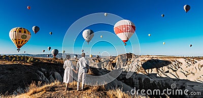 A couple in love stands against the background of balloons in Cappadocia, panorama. Travel to the tourist places of Turkey. Stock Photo