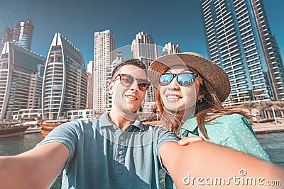 Couple in love takes a selfie in a seaport with a view of huge skyscrapers. Romantic honeymoon trips to Dubai Marina Stock Photo