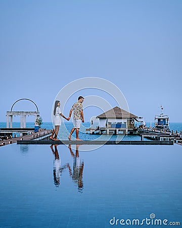 Couple on luxury vacation in Thailand, men and woman infinity pool looking out over the ocean Stock Photo