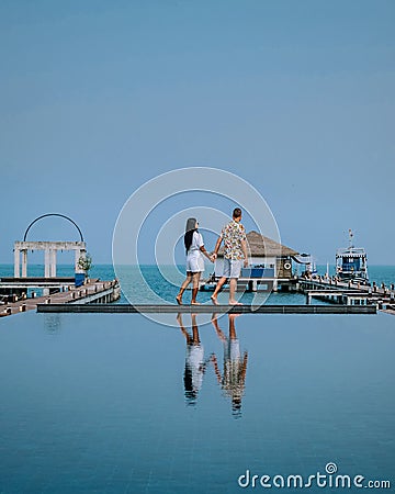 Couple on luxury vacation in Thailand, men and woman infinity pool looking out over the ocean Stock Photo