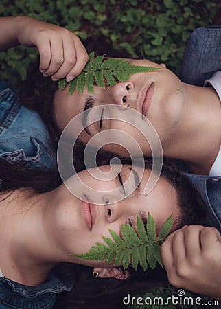 Couple lying in the woods next to each other with a leaf on their face Stock Photo
