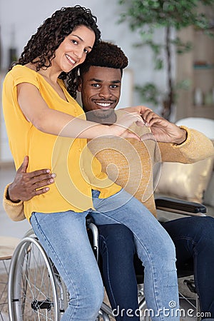 couple make heart gesture with hands man in wheelchair Stock Photo