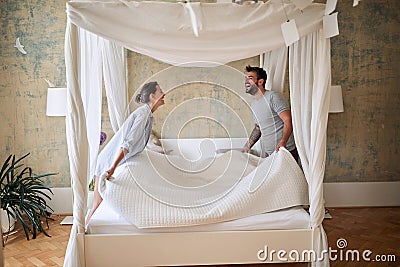 Couple making bed.Charming man and woman in love making bed together Stock Photo