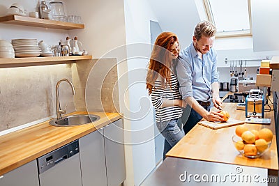 Couple making orange smoothie in kitchen Stock Photo