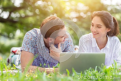 Couple male and women lover using laptop online wireless technology outdoor in the park in holiday vacation together Stock Photo